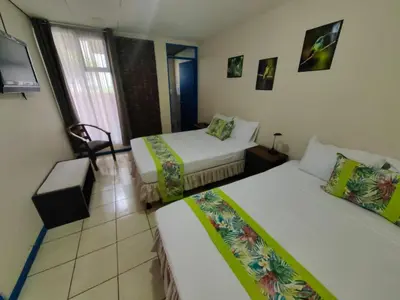 a hotel room with two beds and a tv at Hotel Casa Tago in Alajuela City