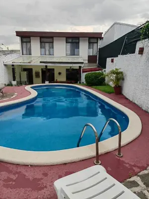 a large blue swimming pool in front of a house at Hotel Casa Tago in Alajuela City