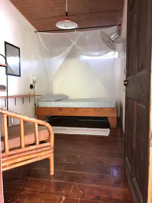 a small room with a bed and a wooden floor at Casa Morpho Uvita Guesthouse in Uvita