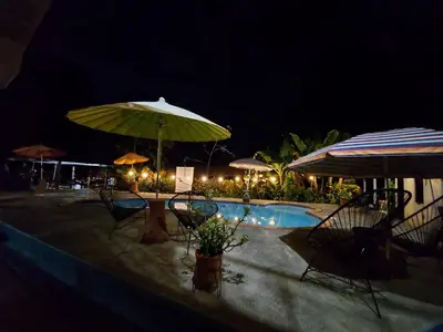a swimming pool with chairs and umbrellas at night at Hotel Sueños de María in Uvita