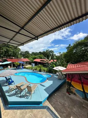 a large swimming pool with chairs and a umbrella at Hotel Sueños de María in Uvita