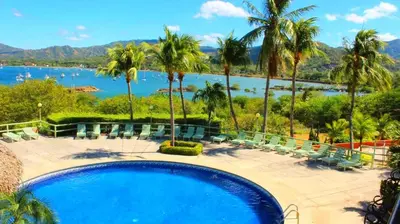 a swimming pool with chairs and a view of a lake at Flamingo Marina Hotel in Playa Flamingo