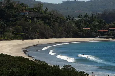 a beach with a group of people surfing in the water at Flamingo Marina Hotel in Playa Flamingo
