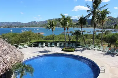 a swimming pool with chairs and a view of the water at Flamingo Marina Hotel in Playa Flamingo