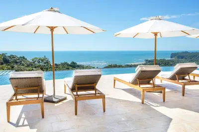 a group of chairs and umbrellas next to a pool at Hotel Three Sixty - Adults Only in Ojochal