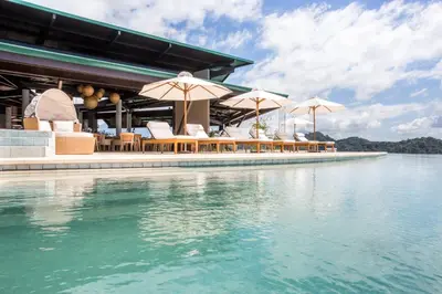 a swimming pool with chairs and umbrellas next to the water at Hotel Three Sixty - Adults Only in Ojochal