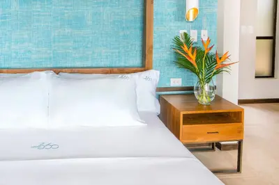 a bedroom with a bed and a table with a vase on it at Hotel Three Sixty - Adults Only in Ojochal