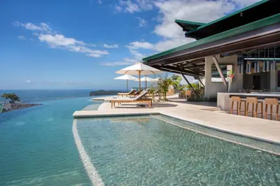 a swimming pool next to a house with the ocean at Hotel Three Sixty - Adults Only in Ojochal