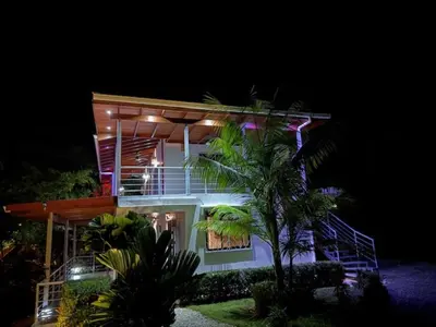 a house at night with a palm tree in front of it at Villas Lambeau 3 Ocean View - 2BR 3 BA in Uvita