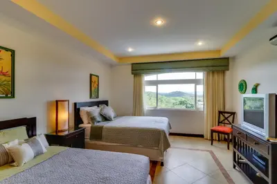 a hotel room with two beds and a television at Naxos 15 in Tamarindo
