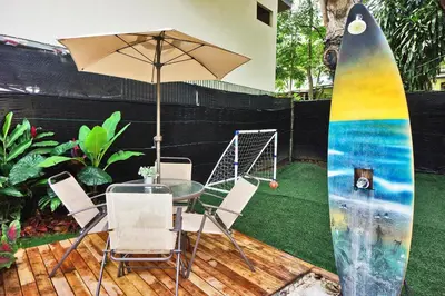 a table and chairs with a surfboard and an umbrella at Villa Picasso in Santa Teresa Beach