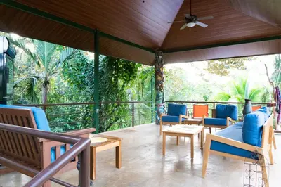 a porch with chairs and tables and a ceiling fan at Arbol Verde Villas in Ojochal