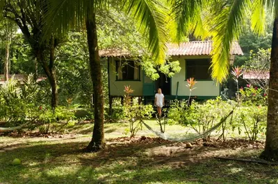a man standing in front of a house with a hammock in front at Casa Grande at Pacuare Reserve in Matina