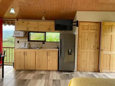 a kitchen with a refrigerator and a counter with a window at Cabaña Niraj in Cartago
