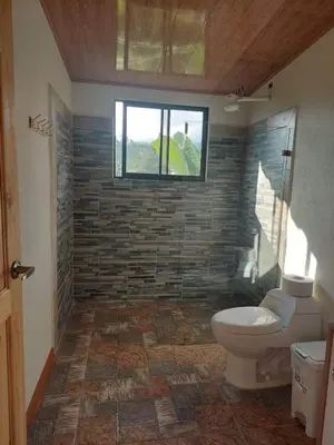 a bathroom with a toilet and a window at Cabaña Niraj in Cartago
