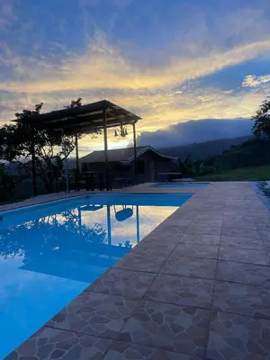 a swimming pool with a gazebo next to a house at Cabaña Niraj in Cartago