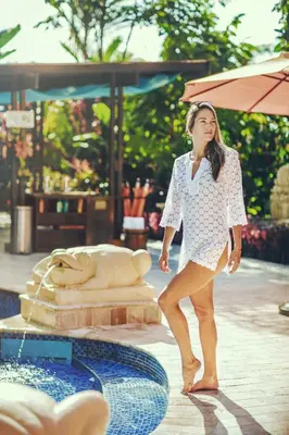a girl in a white dress standing next to a fountain at Nayara Gardens in Fortuna