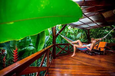 a woman sitting in a hammock on a porch at Nayara Gardens in Fortuna