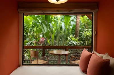 a room with a bed and a balcony with a table at Nayara Gardens in Fortuna