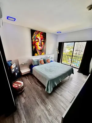 a bedroom with a bed with a painting on the wall at Luxury Condo at Jaco Bay, Costa Rica's best beach in Jacó