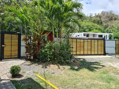 a house with a gate and a fence with palm trees at Trebolmar Apartments for remote work in Santa Teresa Beach