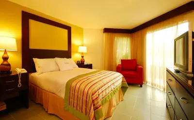 a hotel room with a bed and a red chair at Fiesta Resort All Inclusive Central Pacific - Costa Rica in El Roble