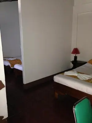 a room with two beds and a table with a lamp at Hotel Don Robert in Puntarenas