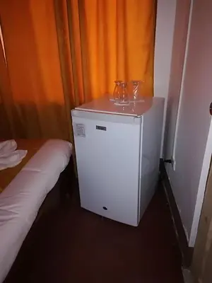 a small refrigerator with two glasses on top of it at Hotel Don Robert in Puntarenas