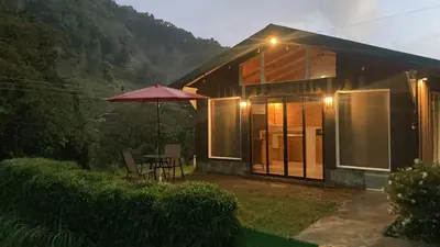 a small house with a table and an umbrella at Los Lagos Lodge in San Gerardo de Dota