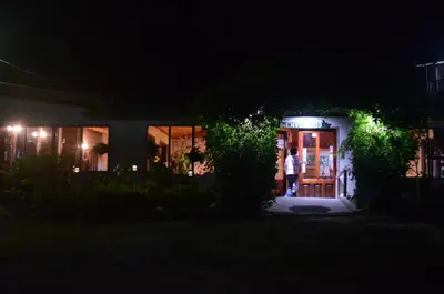 a man standing outside of a house at night at Los Lagos Lodge in San Gerardo de Dota