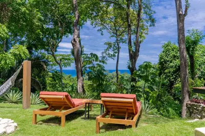 two chairs and a table in the grass at Villa Makai Santa Teresa in Santa Teresa Beach