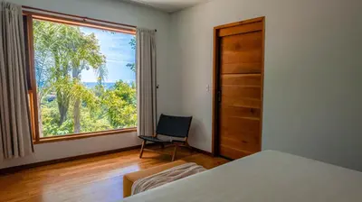 a bedroom with a bed and a chair and a window at Villa Makai Santa Teresa in Santa Teresa Beach