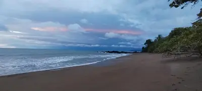 a beach with a cloudy sky and the ocean at Cabins yafeth osa drake bay in Drake
