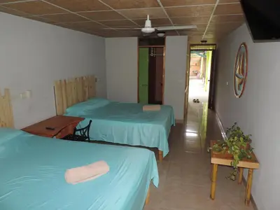 a room with two beds and a table in it at chez philippe in Orotina