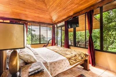 a bedroom with a bed in a room with windows at Boutique Hotel Las Cascadas in Manuel Antonio