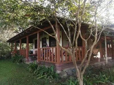 a cottage with a porch and a tree at La Flor de Loto in Cartago