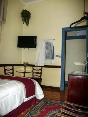 a bedroom with a bed and a tv and a table at Hotel Santo Tomas / Historical Property in San José