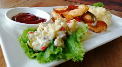 a white plate of food with a salad and ketchup at EYA Ecolodge in San Isidro
