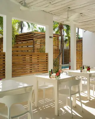 a dining room with white tables and white chairs at BOHO Tamarindo in Tamarindo