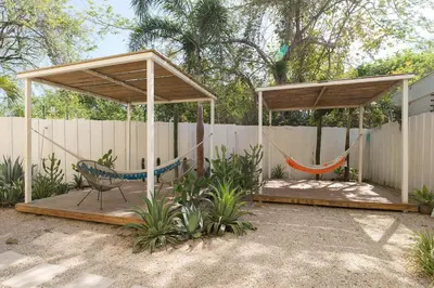 a patio with a hammock and a fence at BOHO Tamarindo in Tamarindo
