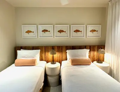 two beds in a room with fish prints on the wall at BOHO Tamarindo in Tamarindo