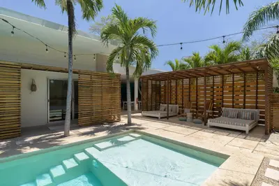 a swimming pool in front of a house with palm trees at BOHO Tamarindo in Tamarindo