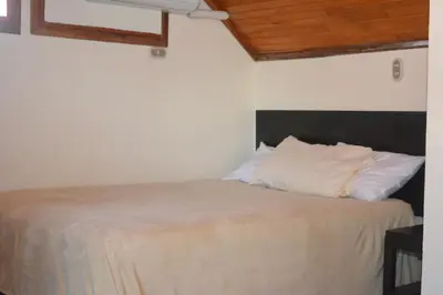 a bedroom with a bed with white sheets and wooden ceilings at Hotel Castillo in San José