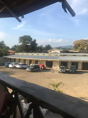 a building with cars parked in a parking lot at Gallina E Palo Beachfront Hotel in Jacó