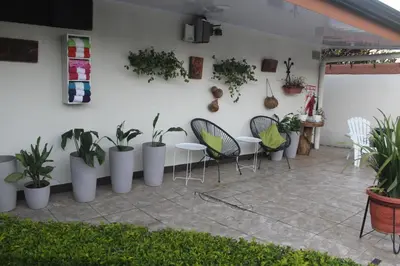 a patio with a bunch of plants and tables and chairs at Berlor Airport Inn in Alajuela City