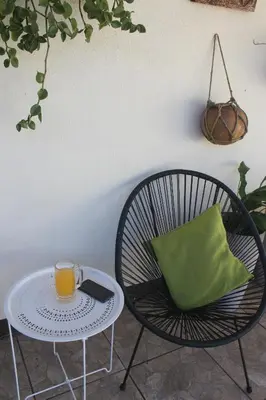 a glass of orange juice sitting on a table with a chair at Berlor Airport Inn in Alajuela City