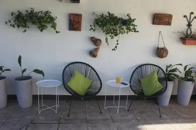 two chairs and a table and some plants on a wall at Berlor Airport Inn in Alajuela City