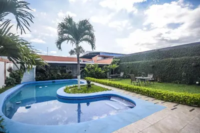 a swimming pool in a yard with a palm tree at Berlor Airport Inn in Alajuela City