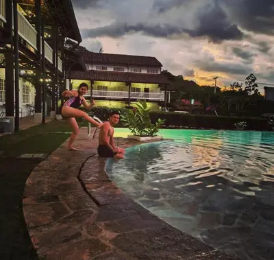 a woman standing next to a man next to a swimming pool at Hotel Luisiana in San José