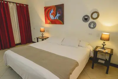 a bedroom with a bed and two tables with lamps at Hotel Luisiana in San José